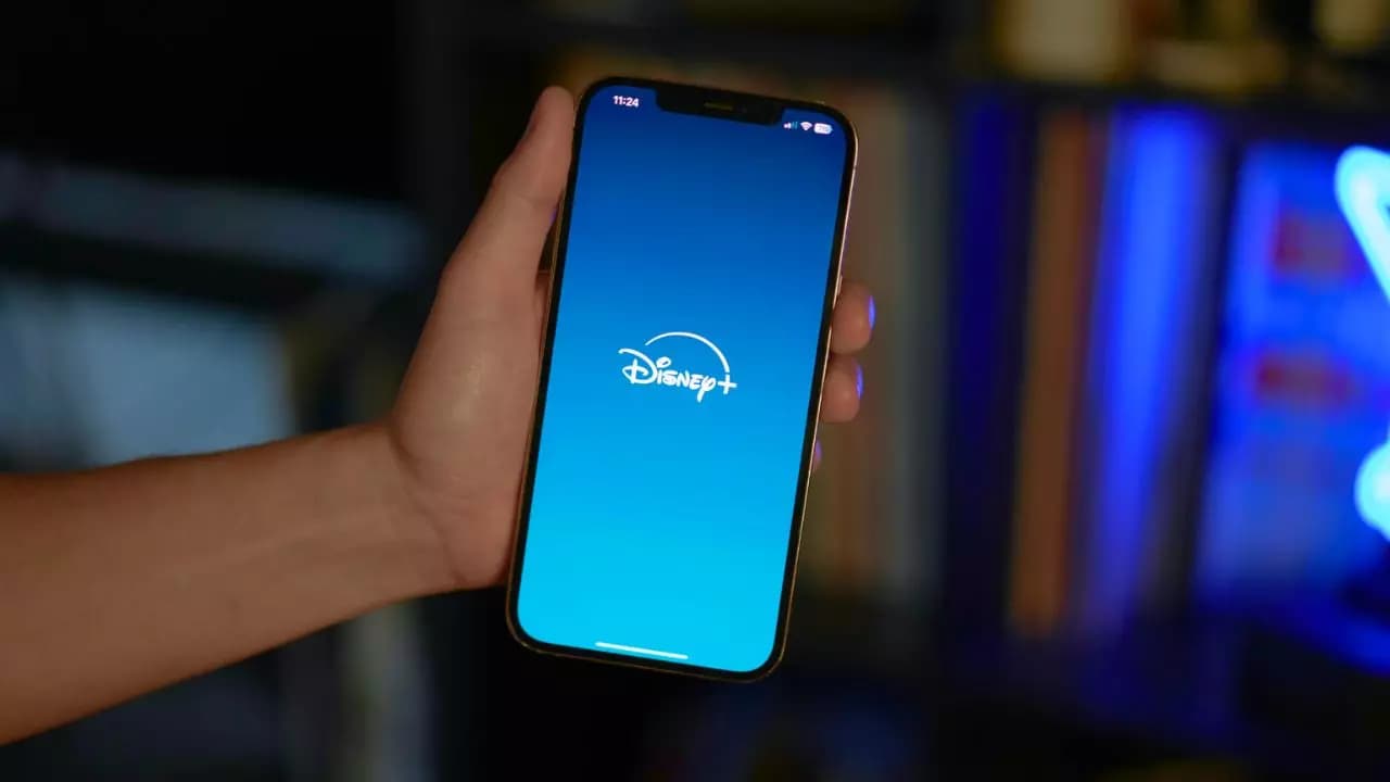 Sujetando-smartphone-logo-Disney-Plus-pantalla Sujetando-smartphone-logo-Disney-Plus-pantalla