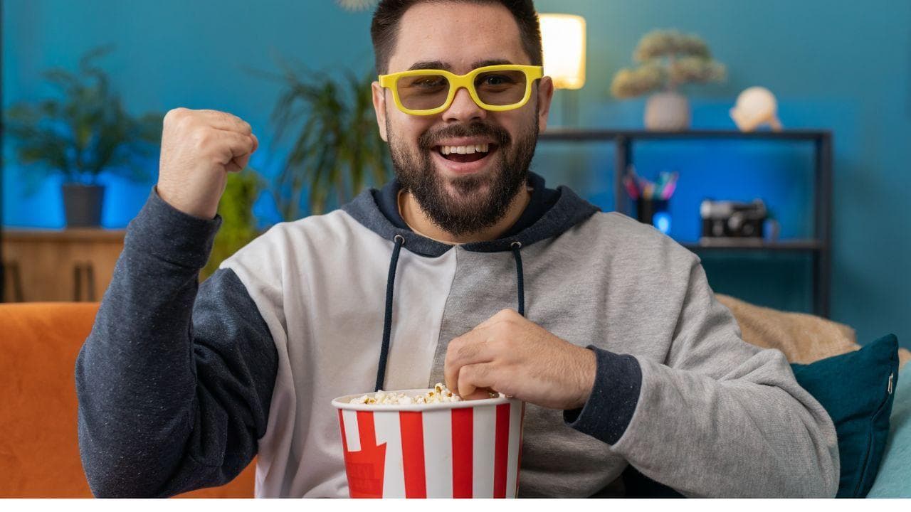 Chico feliz comiendo palomitas levanta brazo Chico feliz comiendo palomitas levanta brazo