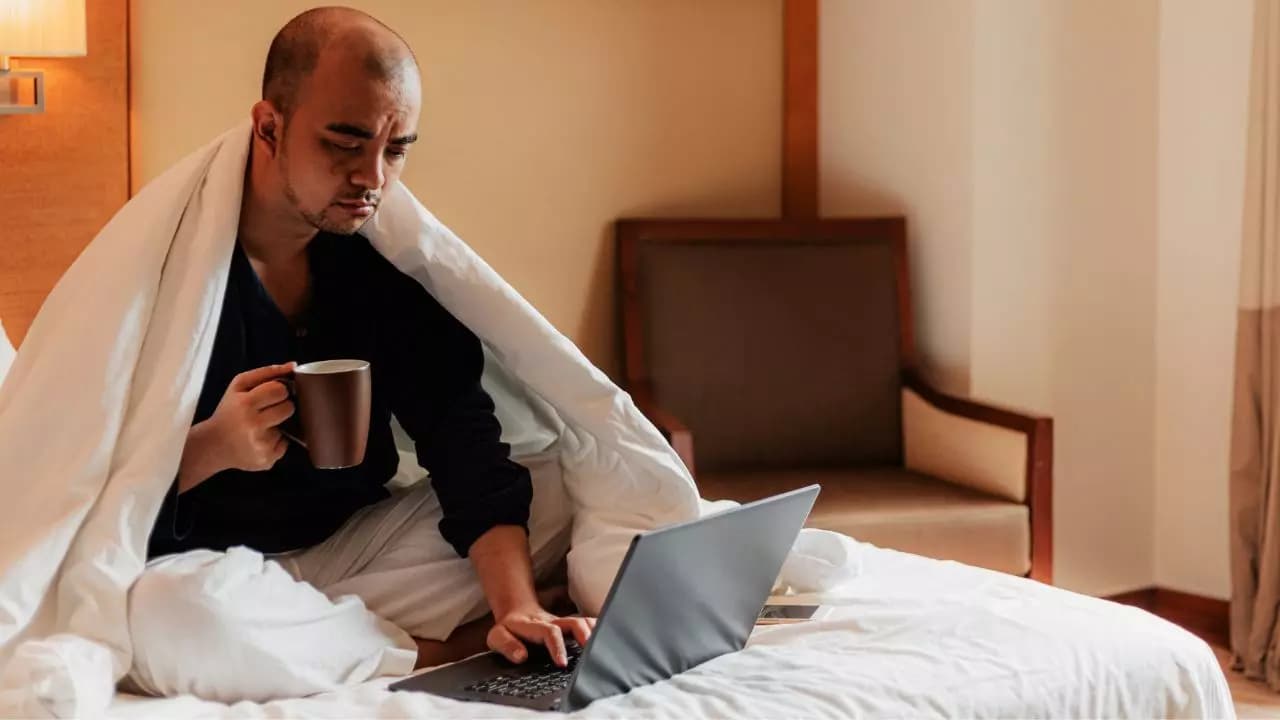 Hombre triste usando portatil cama Hombre triste usando portatil cama