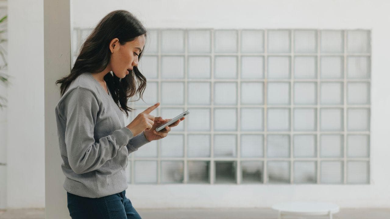 Chica tocando telefono movil estando pie Chica tocando telefono movil estando pie